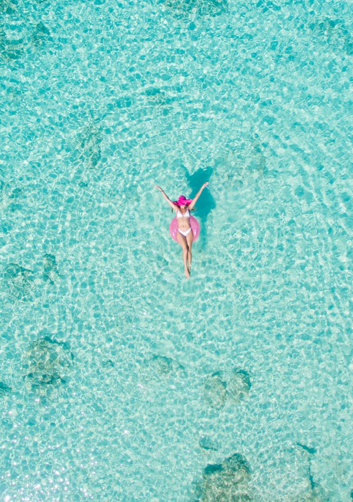 Woman lounging on a pink pool float in the Cayman Islands.