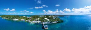 blue water and blue skies with clouds, corner of island with luxury home and dock